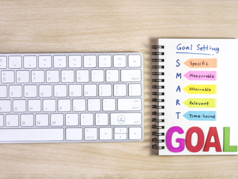 smart goals setting written on the notebook smart goals setting written on the notebook and keyboard over wooden table, business success concept
